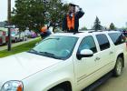 Salutatorian Hadley Binstock uses the sunroof on the family vehicle to have some fun during the parade.
